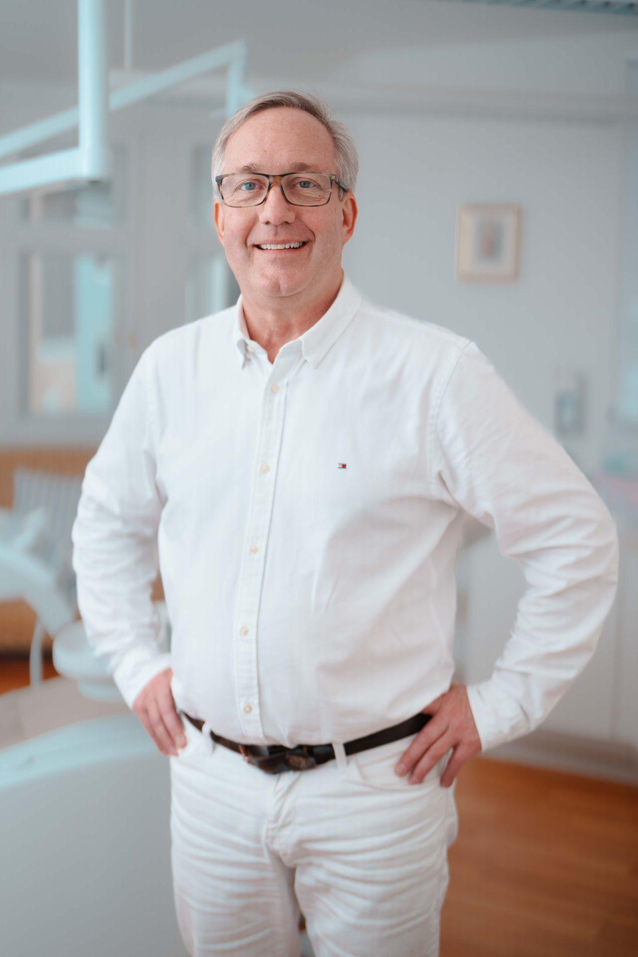 Dr. med. dent. Christian Leunig in weißem Hemd in der Zahnpraxis am Inn